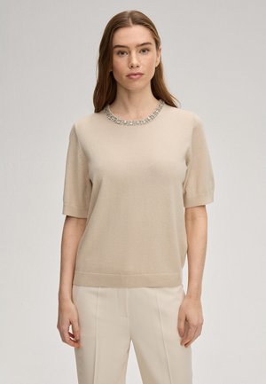 Beiger kurzärmeliger Pullover mit rundem Ausschnitt, verziert mit einem funkelnden Strassbesatz, aus weichem Strickmaterial hergestellt.