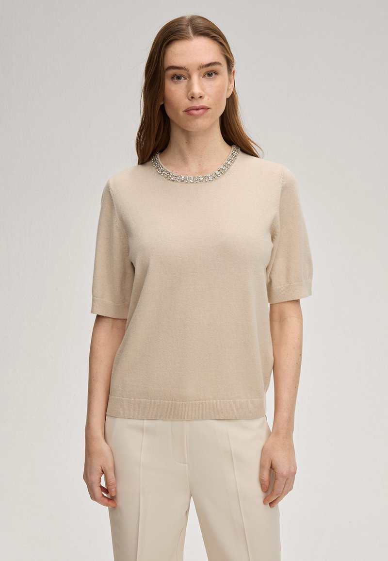 Beige korte mouw trui met een ronde halslijn, versierd met een sprankelend strasslint, gemaakt van zacht gebreid materiaal.