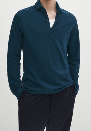Marineblaues Langarm-Poloshirt mit V-Ausschnitt und Knopfleiste; aus weichem, strukturiertem Stoff; figurbetonter Schnitt und lässiges Design.