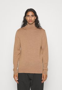 Maglione a collo alto marrone chiaro realizzato in tessuto morbido, con un design aderente, maniche lunghe e un leggero accento del logo sul petto.