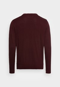 Bordeauxfärgad tröja i pulloverstil gjord av ett slätt stickat tyg. Den har långa ärmar, en rundad halsringning och subtila ribbade detaljer vid ärmsluten och nederkanten.