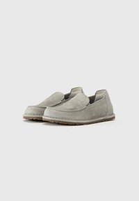 Suede slip-on shoes in light gray, featuring a rounded toe, minimal stitching, and a textured rubber sole for grip.