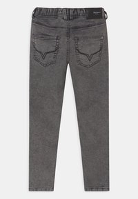 Szare dżinsy slim-fit z elastycznym pasem, tylne kieszenie ze szczegółowym szwem oraz skórzaną metką z logo na prawej stronie.