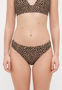 Leopard print bikini set in tan and black tones. The top features a V-neck design, while the bottoms have a low-rise cut with seamless edges.