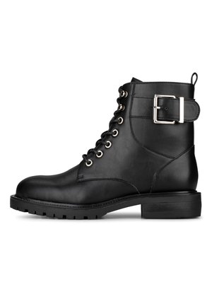 Stivale alla caviglia in pelle nera con suola spessa, lacci sul davanti, occhielli metallici e un grande dettaglio in cinturino argento sulla lato.