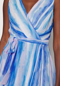 Vestido envolvente de estilo acuarela en azul con un profundo escote en V, que presenta una cintura anudada y una tela fluida que cae con elegancia.
