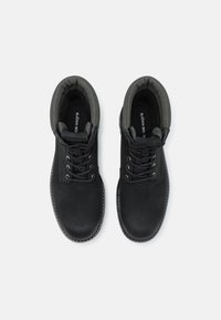 Stivali alla caviglia neri in suede, con punta rotonda, colletto imbottito grigio e lacci neri. Logo stampato all'interno della scarpa.