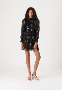Rochie neagră cu motive florale, cu mâneci transparente, talie elastice și croi lejer. Prezintă modele florale delicate în nuanțe de bej și verde.