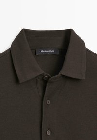 Ciemnobrązowa koszulka polo z fakturowanej tkaniny, z klasycznym kołnierzykiem i trzema brązowymi guzikami. Metka z napisem "Massimo Dutti".