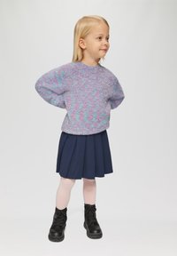 Pull en lilas duveteux avec un col rond, associé à une jupe plissée bleu foncé. Portez-le avec des bottes noires à lacets et des collants rose clair.