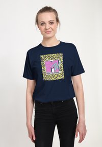 Camiseta azul marino con un gráfico central en rosa y verde con acentos de estampado de leopardo, que muestra el texto "MTV MUSIC TELEVISION".