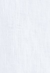 Texture de tissu blanc tissé avec des fils visibles formant un motif en grille, montrant un matériau légèrement translucide et respirant.