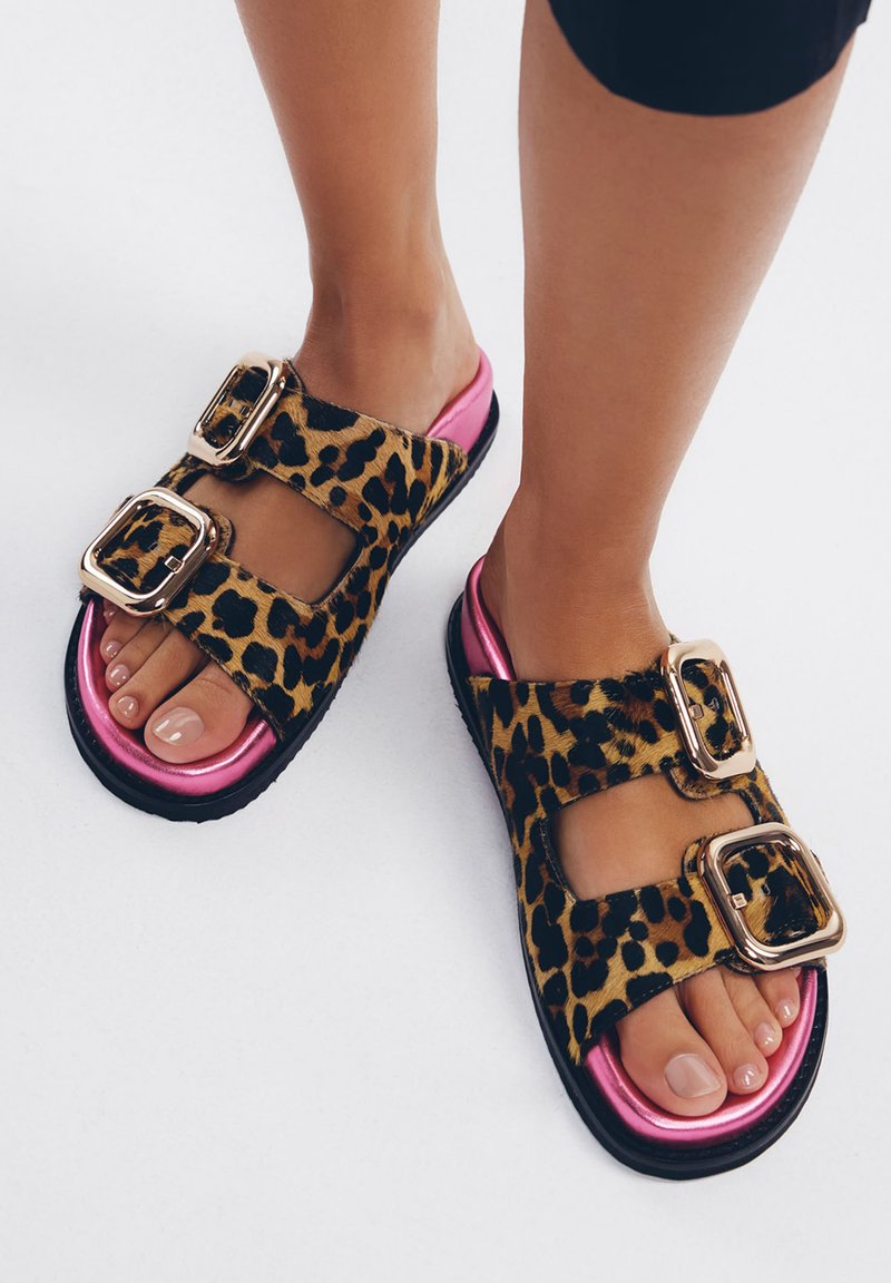 Sandali con stampa leopardo, dotati di due fibbie dorate, dettagli rosa sulla suola e una suola nera testurizzata. Progettati per essere indossati facilmente.