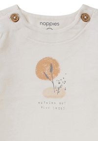 Crème kleurig katoen shirt met houten knoopaccenten bij de nek, met een bedrukte afbeelding van een oranje cirkel en tekst eronder.