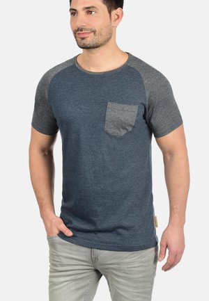 T-shirt a maniche corte blu navy con maniche raglan grigie e taschino sul petto. Realizzato in tessuto morbido, presenta un'etichetta sull'orlo.