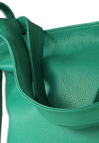 Groene leren shopper met een gestructureerde afwerking, voorzien van twee lange banden en een zachte, nonchalante vorm.