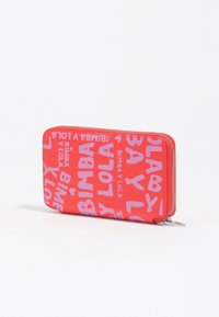 Monedero rojo con cremallera y acabado texturizado, que presenta letras en neón rosa de "BIMBA Y LOLA" en diversas orientaciones y tamaños.