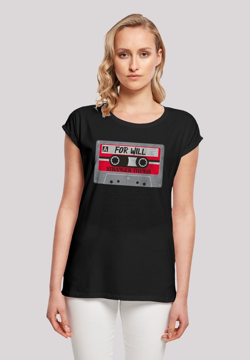 Black short-sleeve t-shirt featuring a printed cassette design with text “A FOR WILL” and “STRANGER THINGS” in red and gray accents.