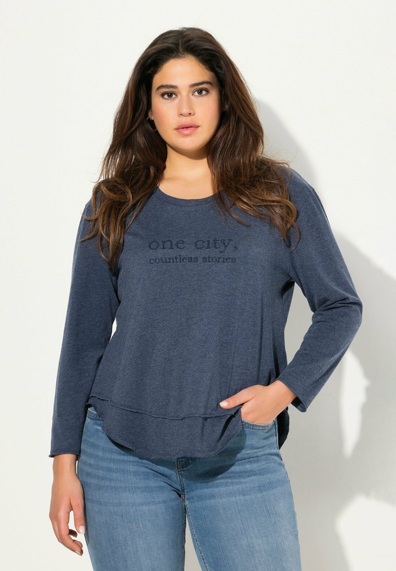 Marineblaue Langarmbluse mit rundem Ausschnitt, versehen mit dem Text "eine Stadt, unzählige Geschichten" in einem leicht erhabenen Design.