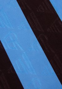 Textiel met afwisselende strepen van zwart en lichtblauw, met reliëfpatronen in het blauwe gedeelte. Over het geheel een zachte, gladde textuur.