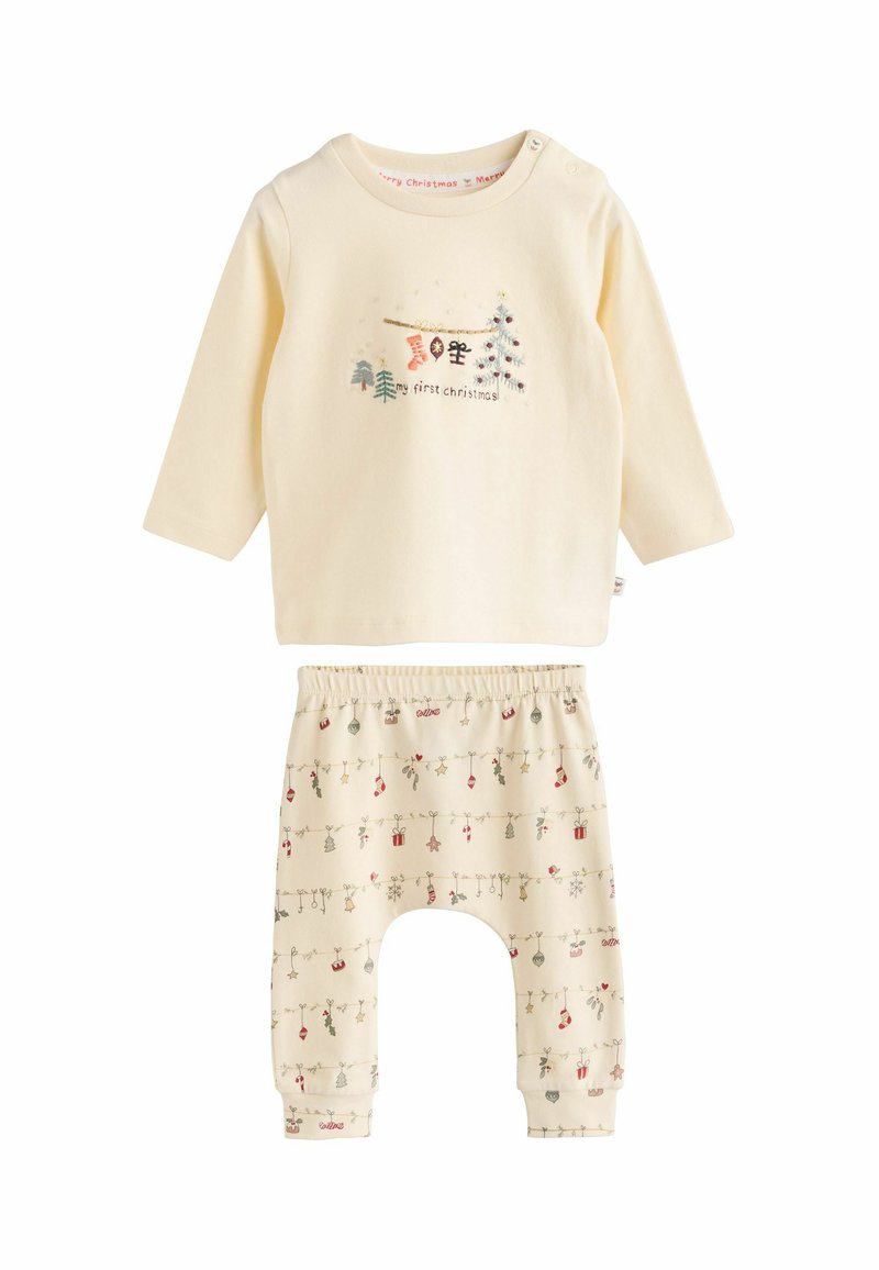 Kremo spalvos dviejų dalių apranga su ilgomis rankovėmis ir užrašu "mano pirmieji Kalėdų" bei raštuotomis kelnėmis, kurios turi šventinius dizainus ir ornamentus.