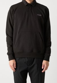 Černá pulovrová mikina s límečkem, přední kapsou a žebrovanými manžetami. Na levé straně hrudníku je vyšitý nápis "BOSS".