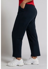 Mörkblå joggers i mjukt material, med sidfickor, rak passform och en bekväm midjeelastik. I kombination med vita sneakers.