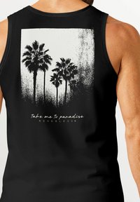 Schwarzes Tanktop mit einem weißen Grafikmuster von Palmen, darunter der Text "Take me to paradise" und "NEVERLESS®" in einer lässigen Schriftart.
