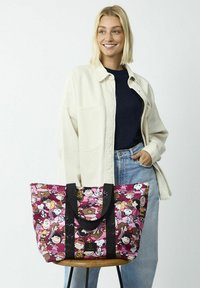 Keerbare tote bag met een roze patroon dat cartoonfiguren laat zien. Zwarte handvatten en een gestructureerde vorm. Gemaakt van duurzaam stof.