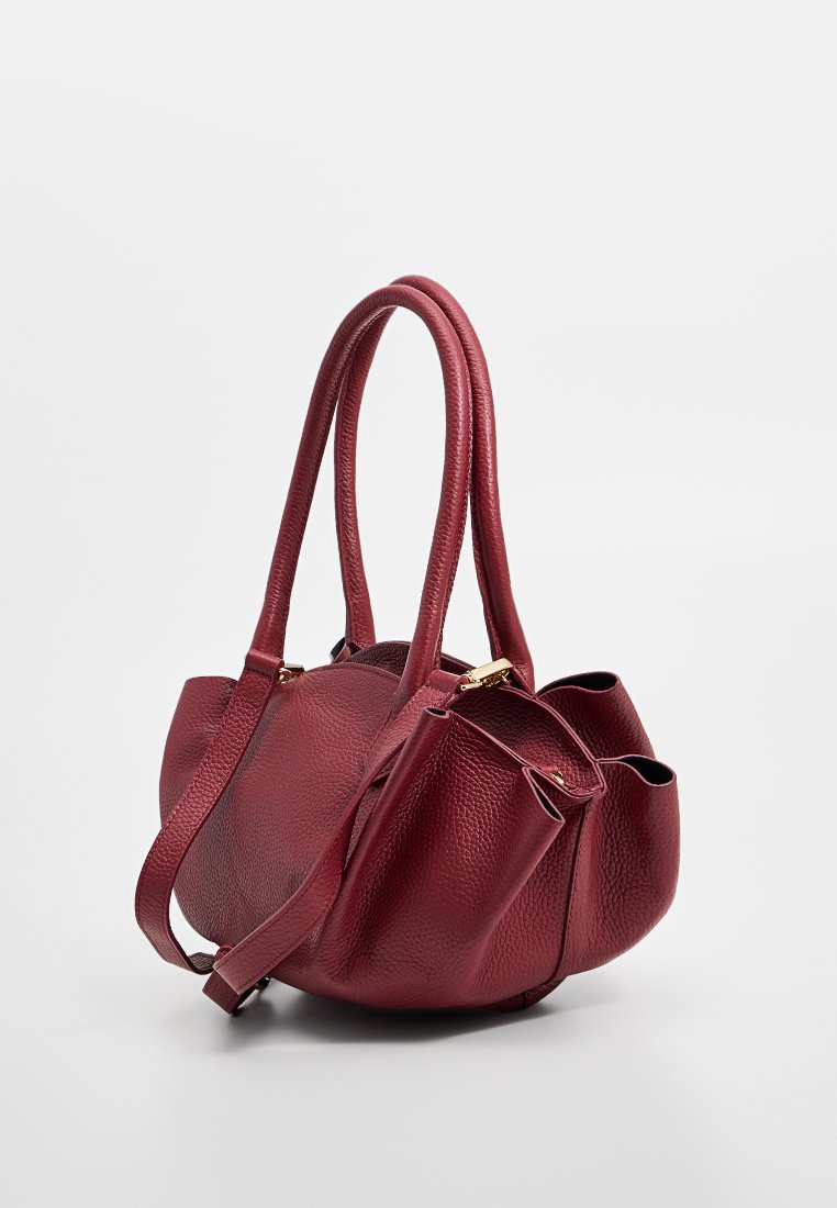 Borsa a mano in pelle rossa con finitura texturizzata, dotata di doppio manico lungo e tracolla regolabile. Presenta un design arricciato e dettagli in metallo dorato.