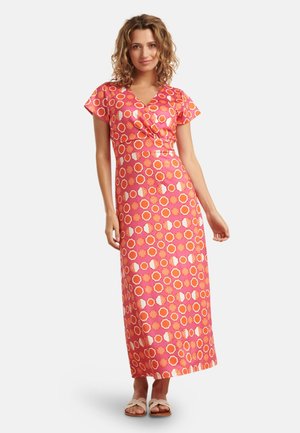 Maxikleid aus pinkem Stoff mit Wickeldesign, kurzen Ärmeln und kreisförmigen Mustern in verschiedenen Farben. Trägt dazu leichte Sandalen.