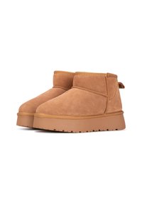 Botas de tobillo de ante marrón claro con punta redondeada, perfil bajo y suela de goma texturizada. Incluyen una costura y una pequeña lengüeta en la parte posterior.
