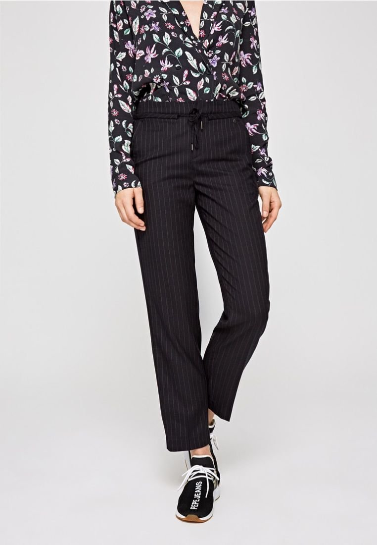 Pantaloni neri a righe con una vita elastica e cordino, abbinati a una blusa a stampa floreale nei toni del nero, bianco e pastello.