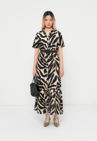 Button-up maxi dress with a black and beige zebra print, short sleeves, belted waist, and side slits, paired with a black bag and gray shoes.