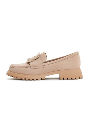 Beiger Wildleder-Loafer mit grober Gummisohle, abgerundetem Zehenbereich, niedrigem Absatz und dekorativem Riemendetail oben.