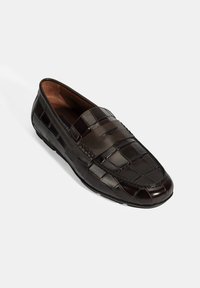 Schwarze Leder-Loafer mit einem strukturierten Krokodilmuster. Mit einem glatten Riemen über der Vorderseite und einer abgerundeten Spitze. Gummisohle.