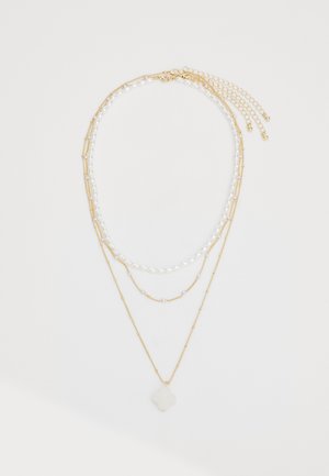 Gouden meerlaagse ketting met parelmoer kralen en een witte stenen pendant. Bevat verschillende kettinglengtes en -texturen.