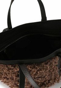 Schwarze Leder-Tote-Bag mit strukturiertem braunem, fellartigem Boden, Innenreißverschlussfach, offenem Oberteil und doppelten Griffen.