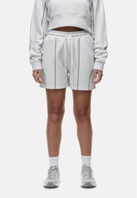 Witte sweatshorts met donkere biesdetails, elastische tailleband en zijzakken, gecombineerd met een bijpassende cropped sweatshirt.