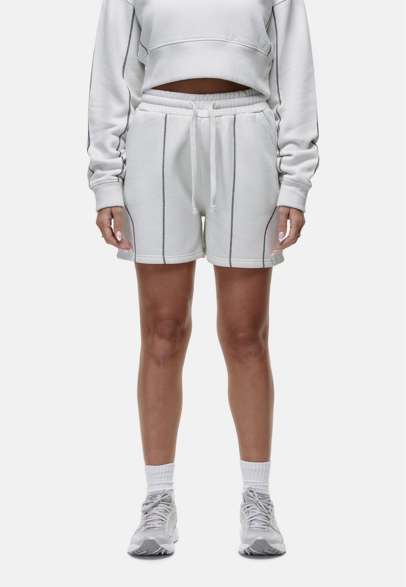 Witte sweatshorts met donkere biesdetails, elastische tailleband en zijzakken, gecombineerd met een bijpassende cropped sweatshirt.