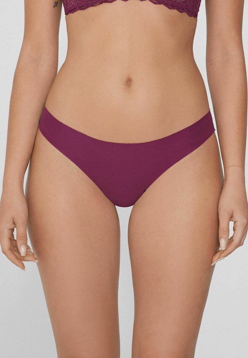 Bikini en coton bordeaux avec une taille élastique lisse et une couverture minimale. Caractéristiques d'un design simple sans motifs visibles ni accents.