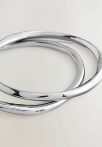 Drei ineinandergreifende metallische Armreifen, kreisförmig, mit einer polierten Silberoberfläche und glatter Textur. Keine sichtbaren Muster oder Akzente.