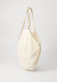 Biała siatkowa torba tote z metalicznymi srebrnymi paskami. Posiada otwartą górę i teksturowaną powierzchnię, idealna do codziennego użytku.