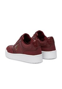 Sneaker bordeaux con dettagli a rilievo, retro testurizzato e suola in gomma bianca. Presenta un logo metallico con marchio sul lato.