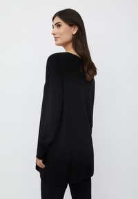Maglione nero a maniche lunghe con una vestibilità comoda e scollatura a V, caratterizzato da polsini e orlo a coste, realizzato in un morbido tessuto testurizzato.