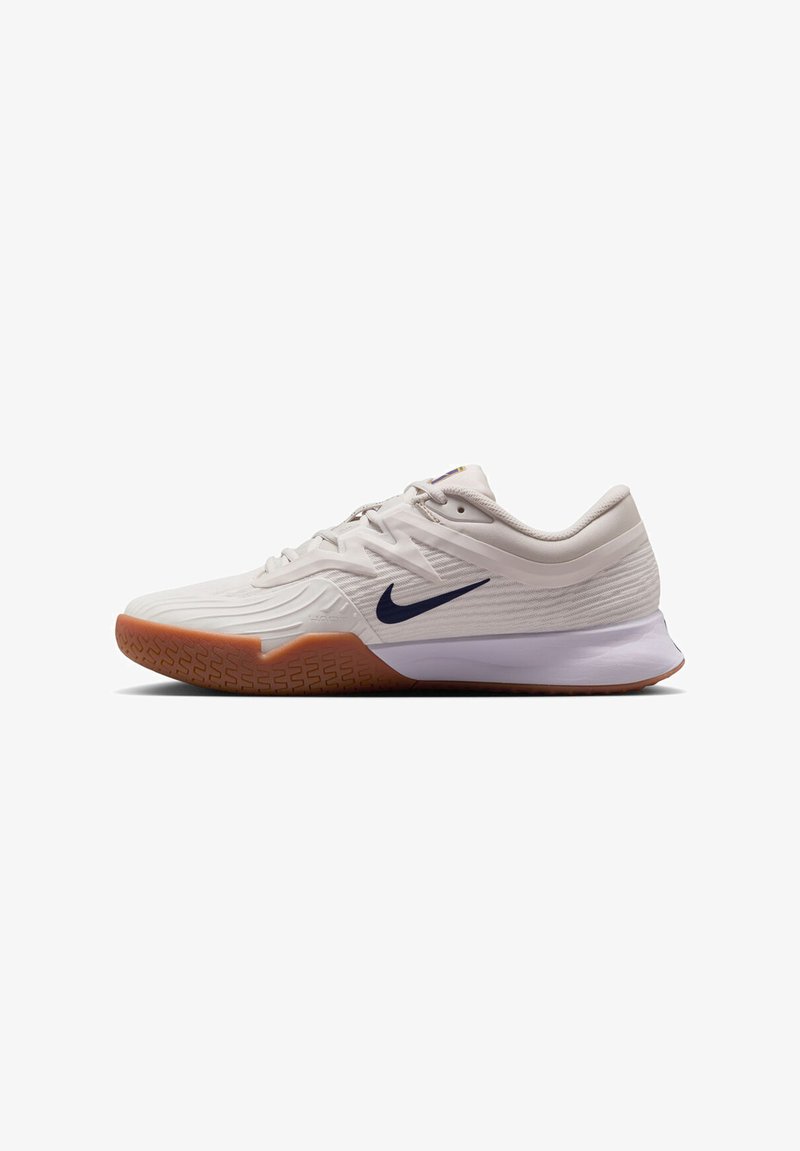 Zapatillas deportivas de color claro con un upper texturizado, que presentan un logo marino prominente, una suela acolchada y una suela de goma.
