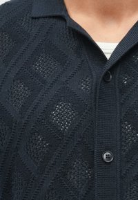 Marineblauwe cardigan met een gestructureerd ruitpatroon, knoopsluiting en een kraag. Gebreide stof met een zachte, ademende kwaliteit.