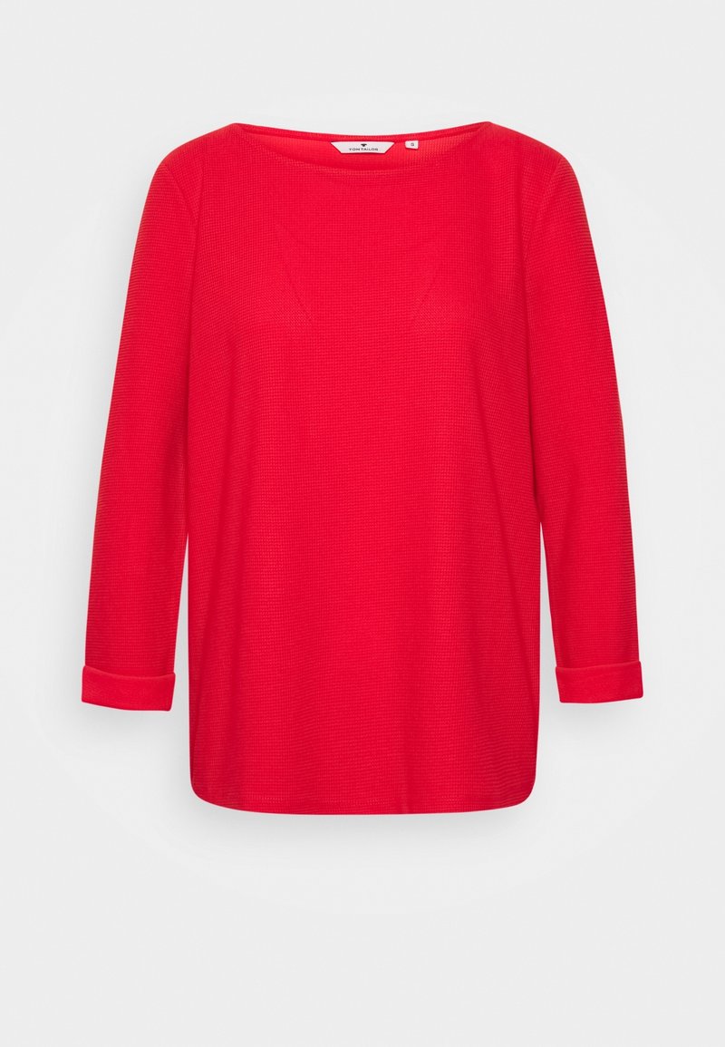 Maglia rossa a maniche lunghe con scollo rotondo e polsini arrotolati. Tessuto strutturato con cuciture sottili. Design semplice, adatto per un abbigliamento informale.