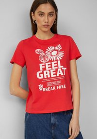 Rode katoenen T-shirt met witte tekst en bloemgraphics, ronde halslijn, korte mouwen en een ontspannen pasvorm. Het ontwerp bevat motiverende zinnen.