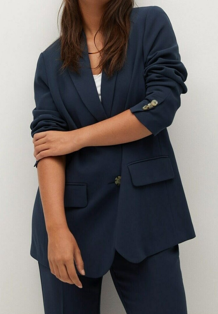 Blazer azul marino hecho de tela suave, con cierre de un solo botón, dos bolsillos delanteros y mangas remangadas con detalle de botón.